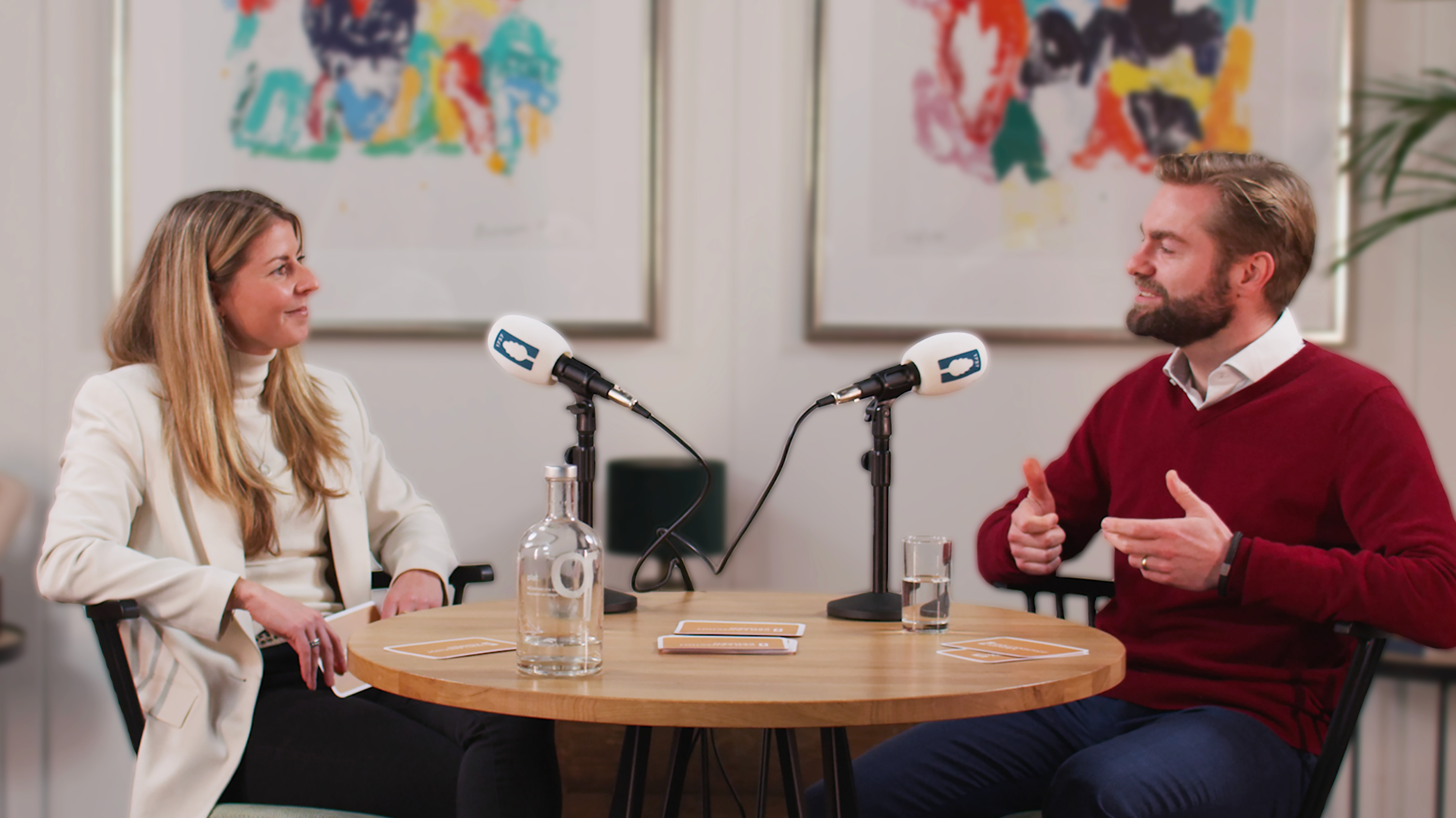 Two people recording a podcast: a woman and a man engaged in a lively conversation, seated at a table with microphones.